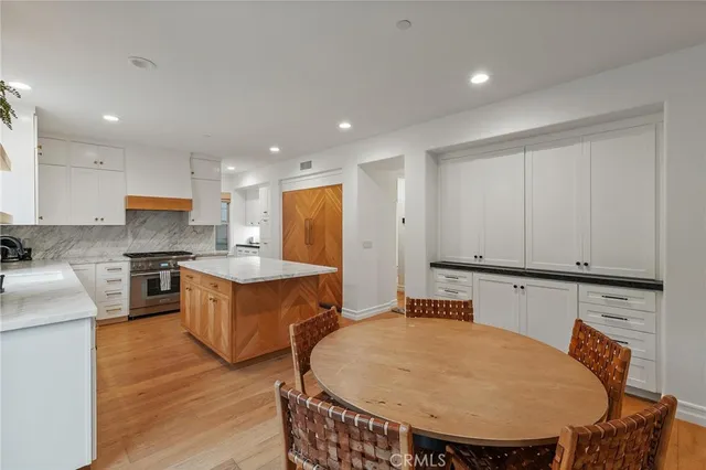 a large kitchen with stainless steel appliances a white table chairs and a refrigerator