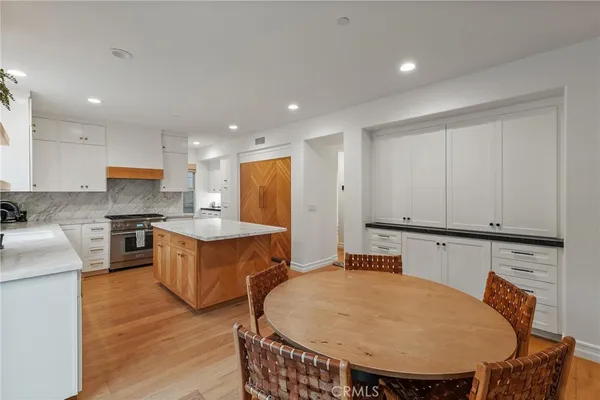 a large kitchen with stainless steel appliances a white table chairs and a refrigerator