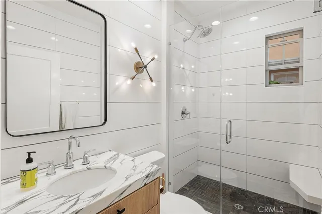 a bathroom with a granite countertop sink a toilet and shower