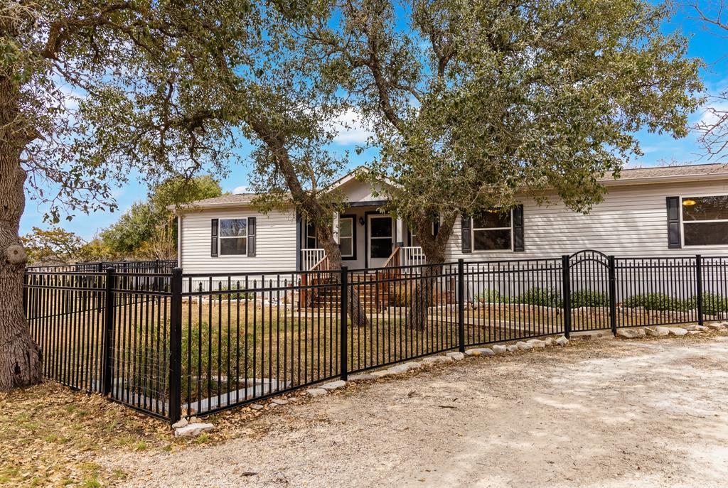 3955 Klein Branch Road Harper, TX 78631 - Photo 1 of 40 a view of a white house with large trees and wooden fence
