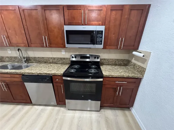 a kitchen with granite countertop a sink and a stove top oven