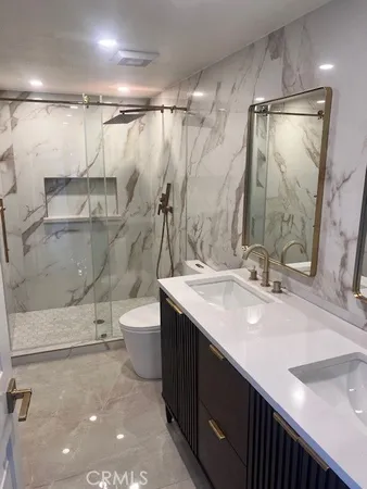 a bathroom with a double vanity sink toilet mirror and shower