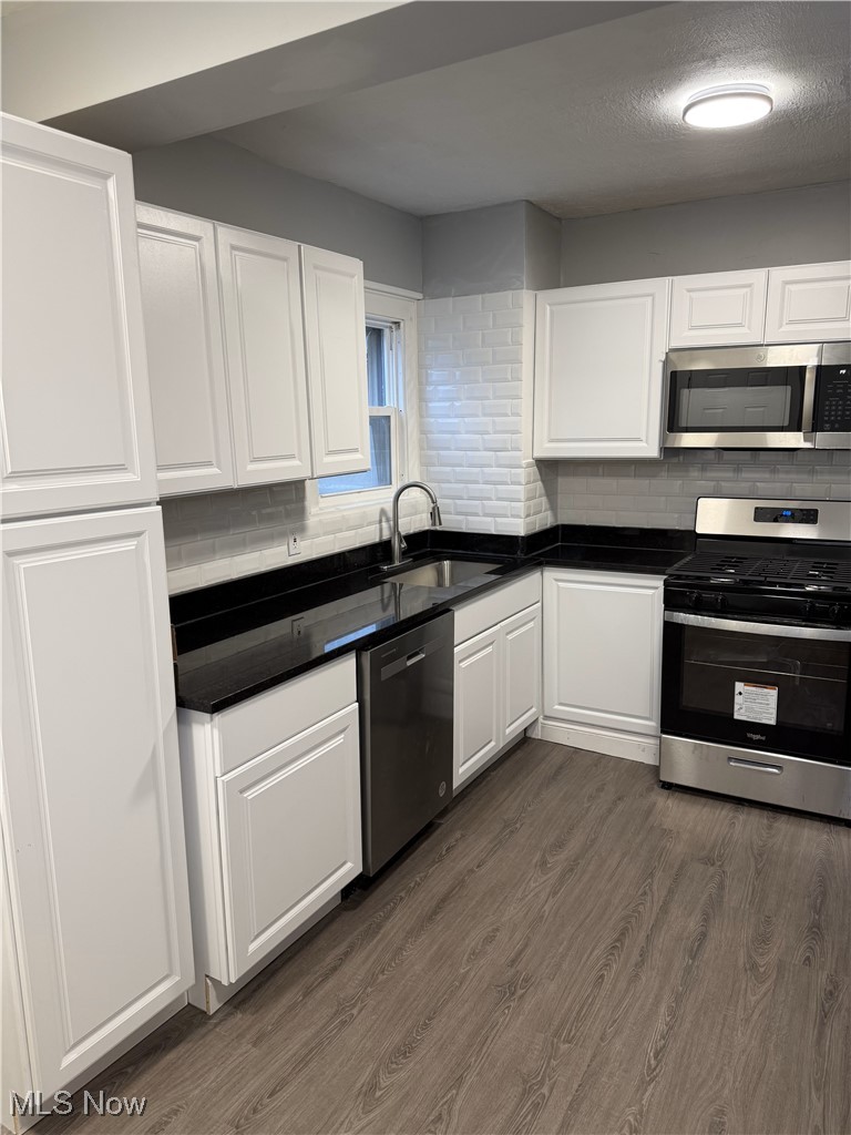 1013 Berwin Street Akron, OH 44310 - Photo 7 of 13 Kitchen with appliances with stainless steel finishes, tasteful backsplash, sink, white cabinets, and dark hardwood / wood-style floors
