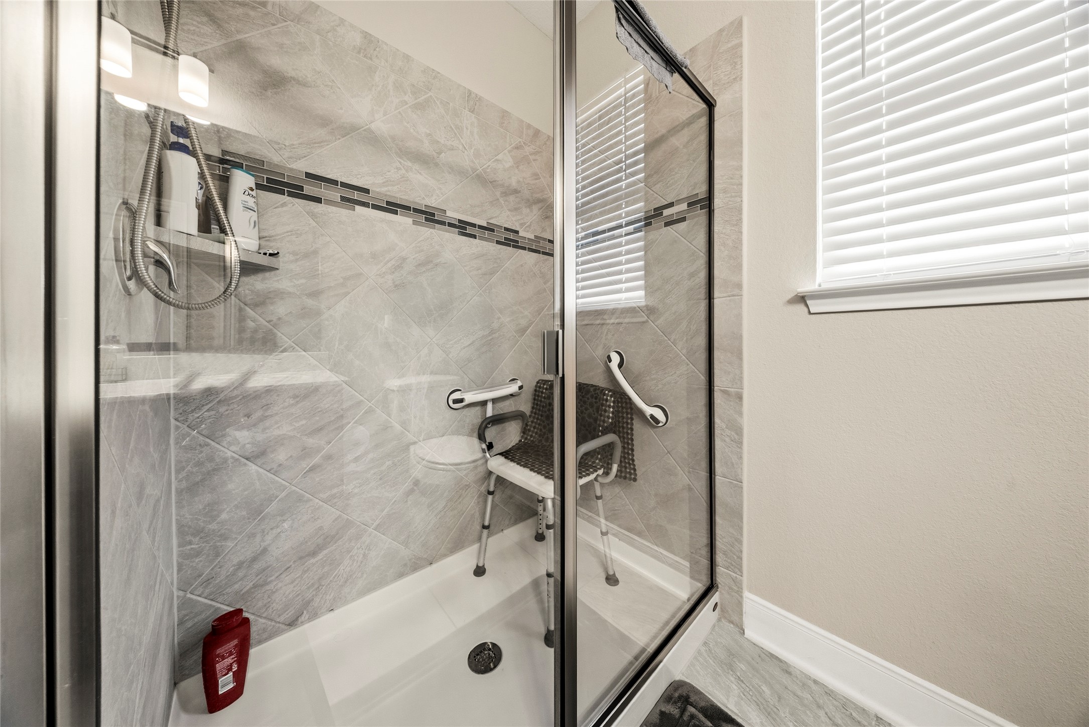 105 West Point Way Elgin, TX 78621 - Photo 12 of 27 Glass-enclosed shower featuring large format tile surrounds, a decorative mosaic tile accent band, and a white shower pan