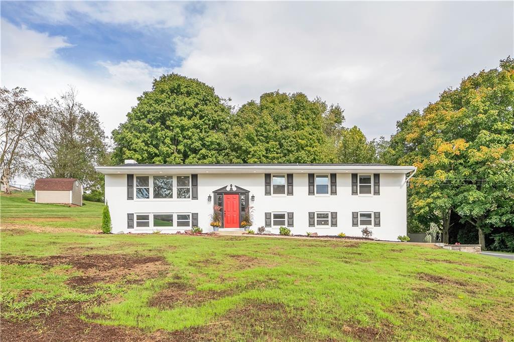a view of a house with a big yard and large trees