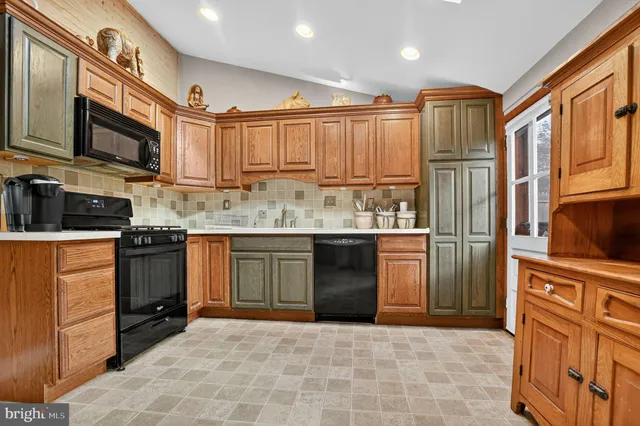 a kitchen with stainless steel appliances granite countertop a stove top oven a refrigerator a sink and dishwasher with white cabinets