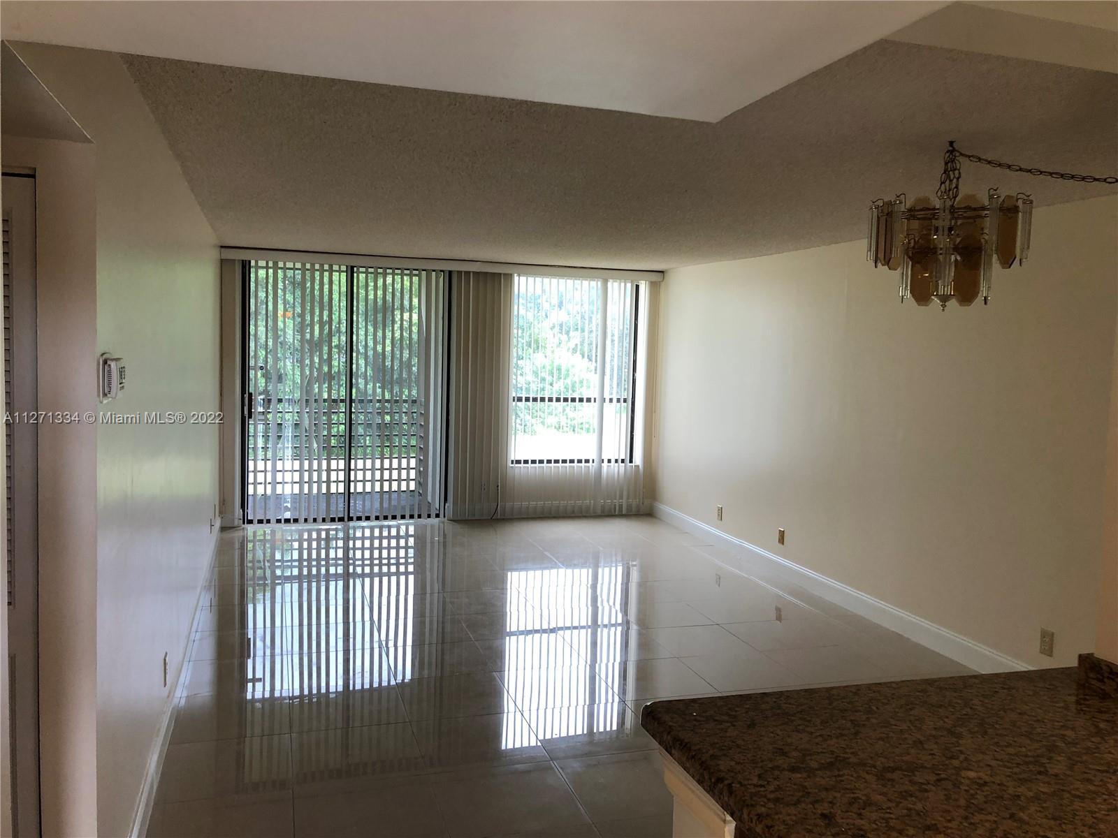 8050 West McNab Road, Unit 216 Tamarac, FL 33321 - Photo 11 of 16 a view of an empty room with wooden floor and a window