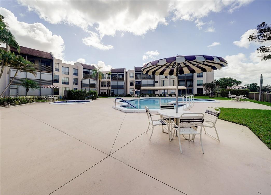8050 West McNab Road, Unit 216 Tamarac, FL 33321 - Photo 2 of 16 a view of a patio with a table and chairs under an umbrella