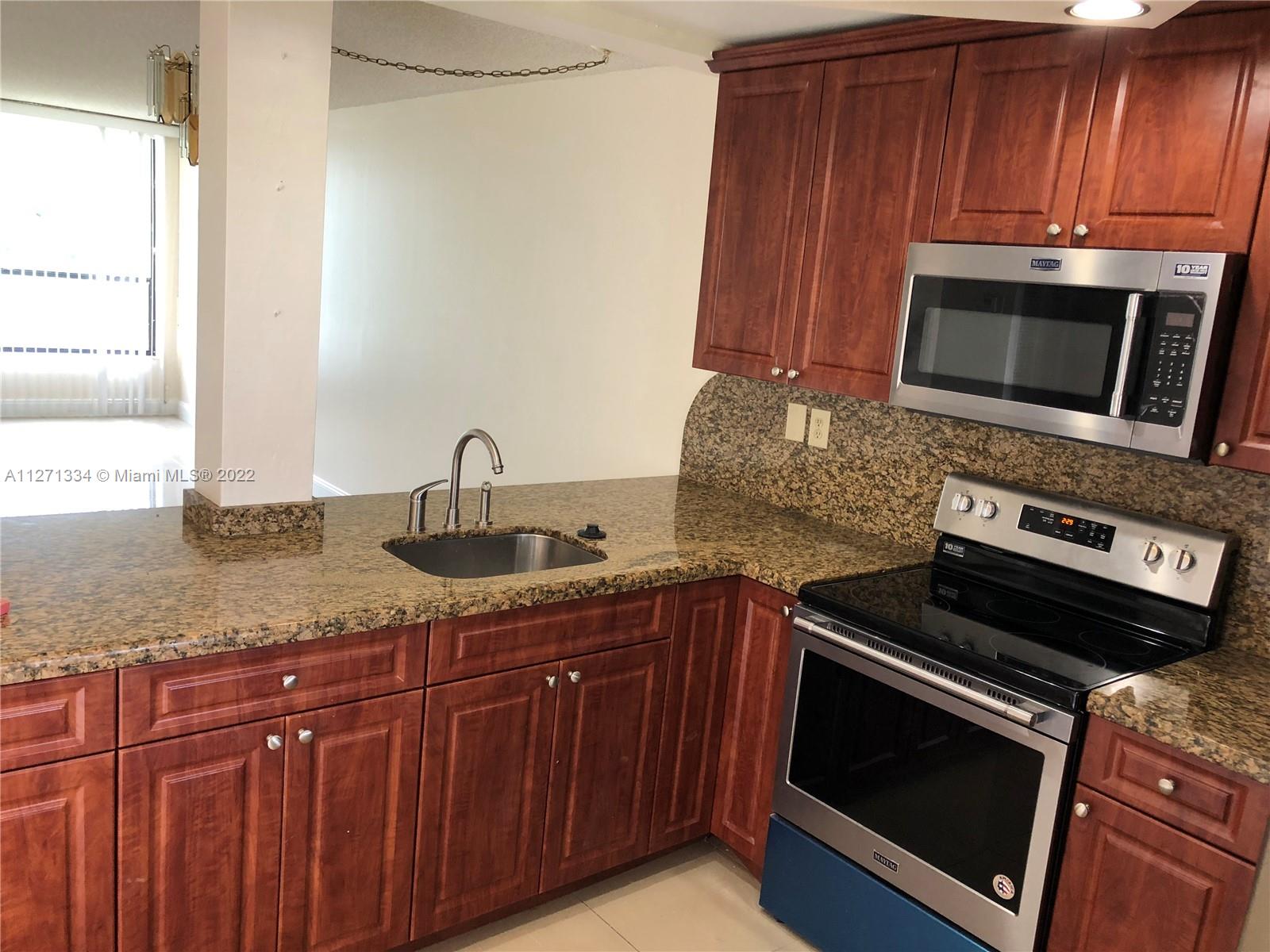 8050 West McNab Road, Unit 216 Tamarac, FL 33321 - Photo 8 of 16 a kitchen with granite countertop a sink stove and microwave