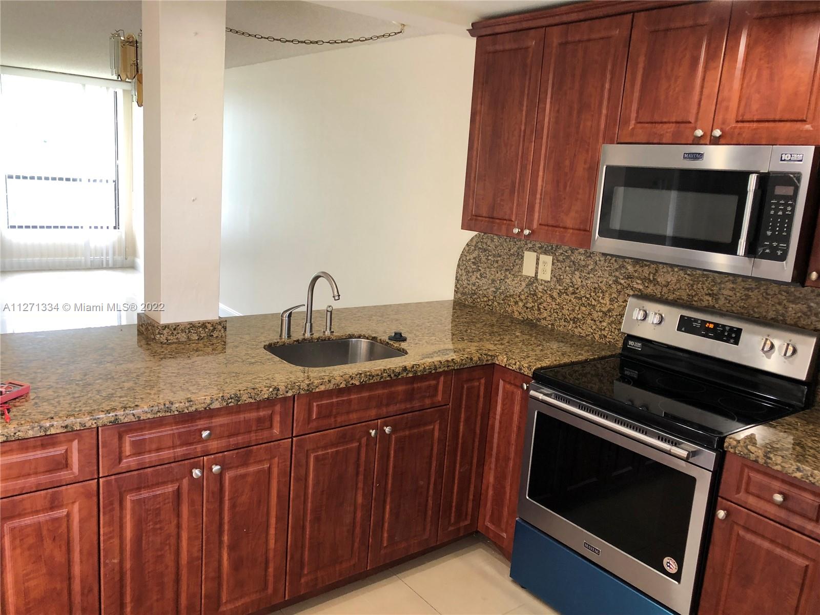 8050 West McNab Road, Unit 216 Tamarac, FL 33321 - Photo 9 of 16 a kitchen with granite countertop wooden cabinets and stainless steel appliances