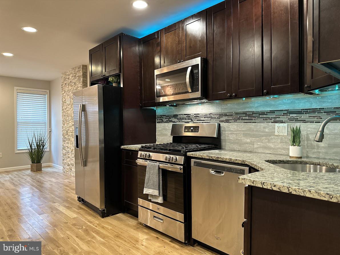 a kitchen with stainless steel appliances granite countertop a stove microwave and refrigerator