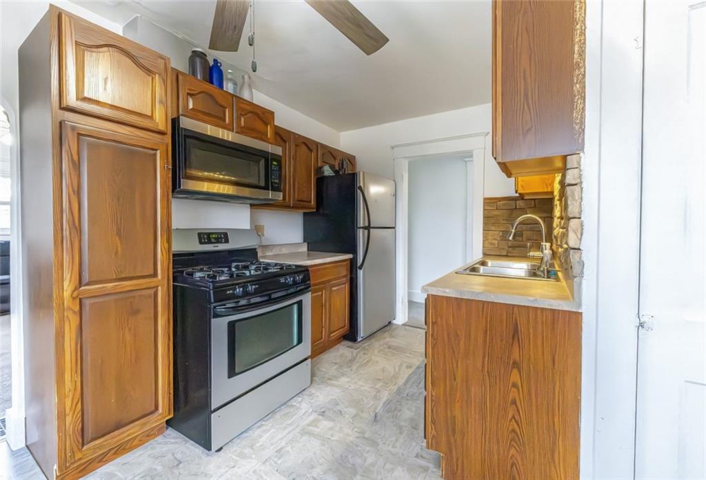 1470 Old Leechburg Road Pittsburgh, PA 15239 - Photo 5 of 25 a kitchen with stainless steel appliances granite countertop a refrigerator a stove and a sink with wooden floor