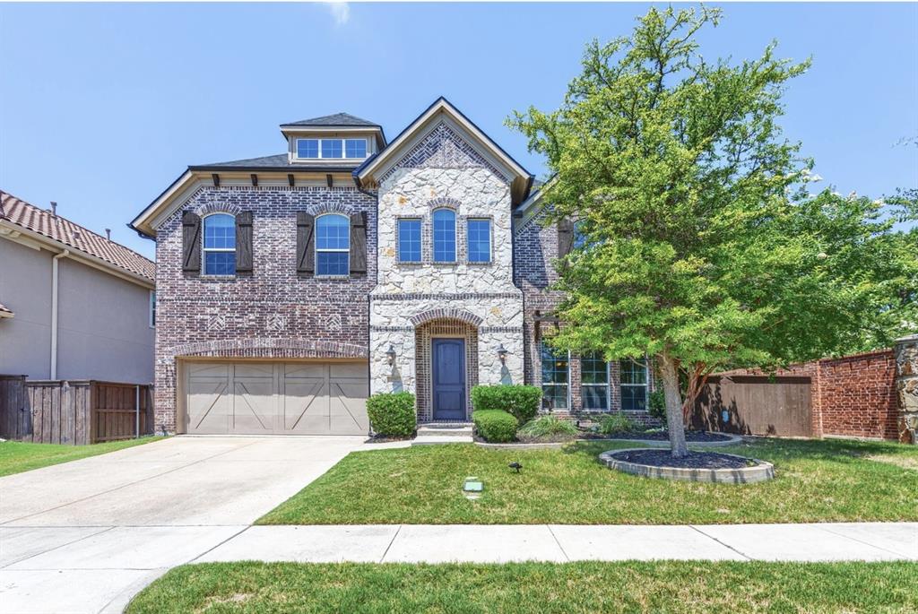 French country inspired facade featuring brick siding, driveway, stone siding, and a garage