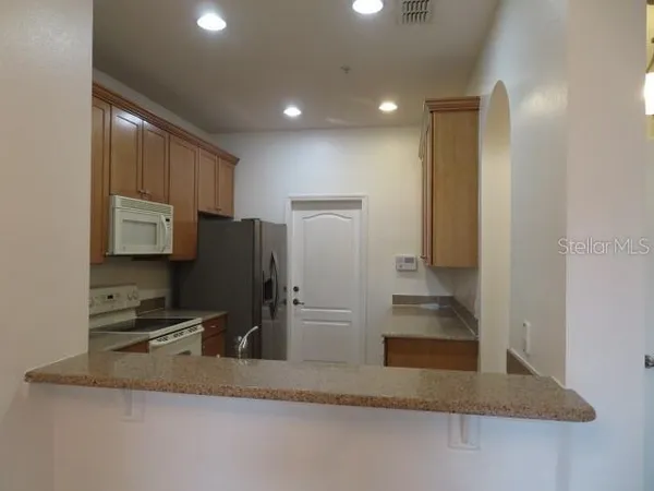a kitchen with a sink a refrigerator and wooden cabinets