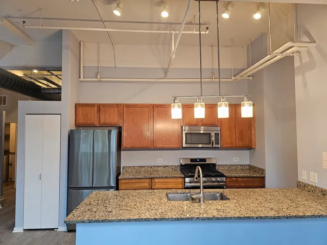a kitchen with kitchen island granite countertop a sink and a refrigerator