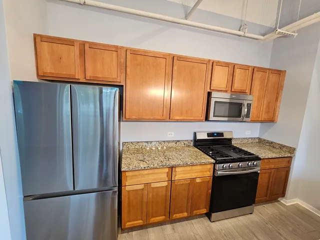 a kitchen with granite countertop stainless steel appliances a refrigerator stove top oven and sink