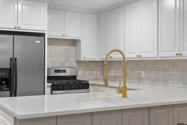 a kitchen with granite countertop a refrigerator a stove and white cabinets