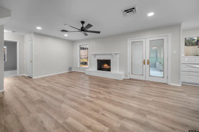 a view of a livingroom with a fireplace a ceiling fan and hardwood floor