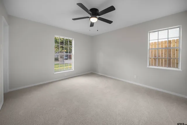 an empty room with a ceiling fan and window