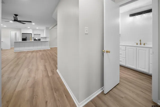 an empty room with wooden floor fan and windows