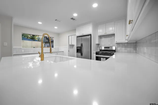 a kitchen with stainless steel appliances a refrigerator and a stove top oven