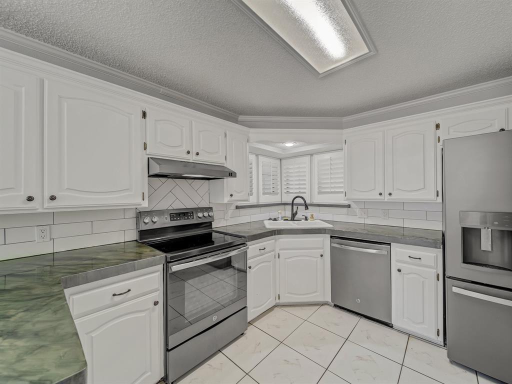121 Northeast Brushy Mound Road Burleson, TX 76028 - Photo 12 of 35 a kitchen with white cabinets stainless steel appliances and sink