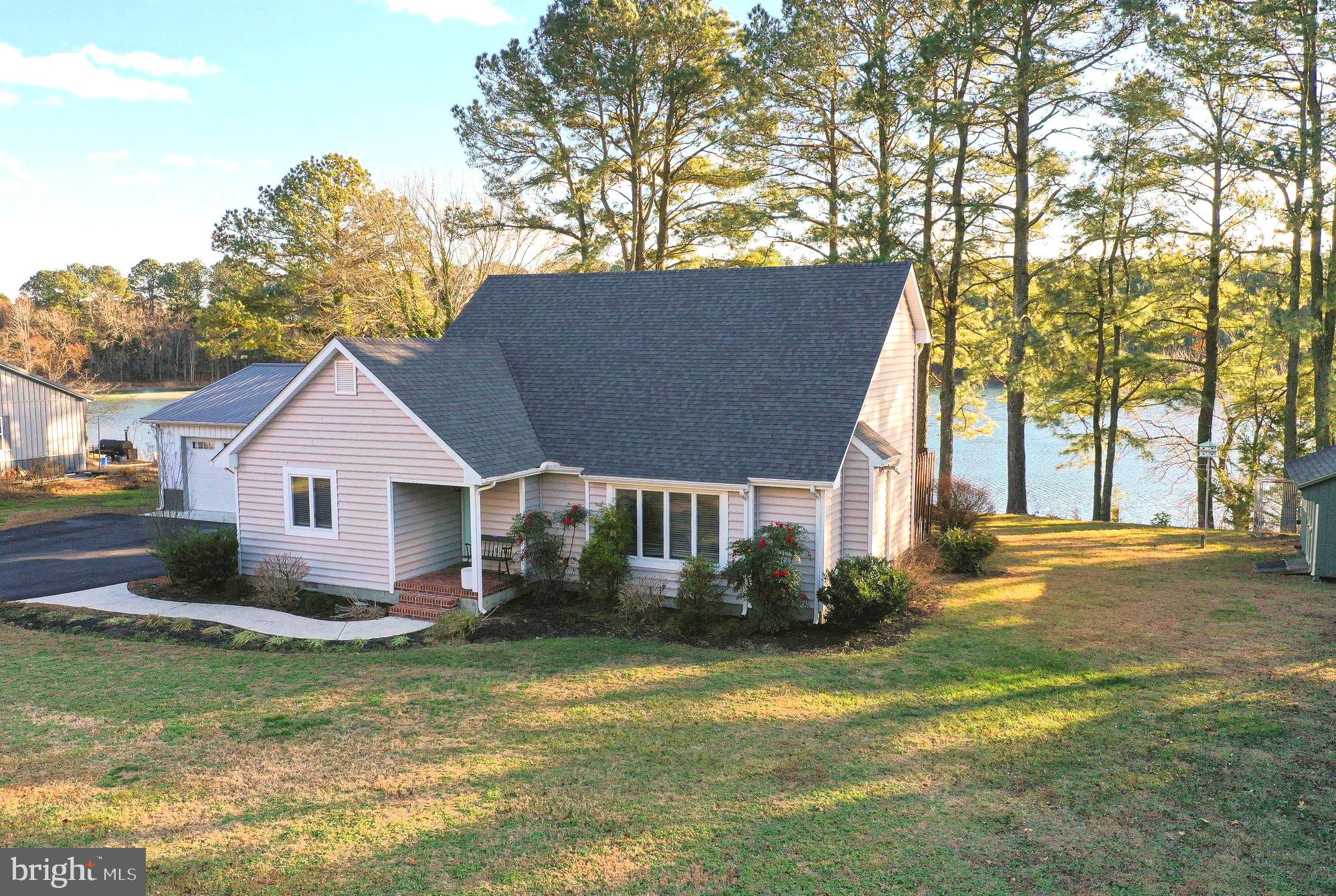 a view of a house next to a big yard and large trees