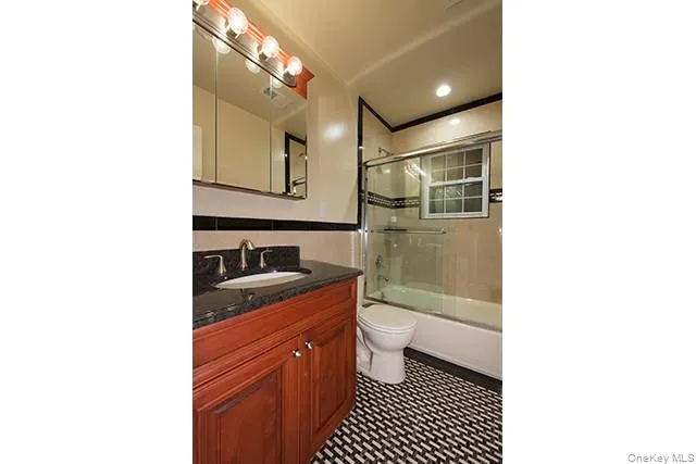 a bathroom with a granite countertop sink a toilet a mirror and shower