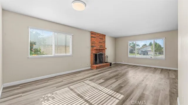 a view of an empty room with window and wooden floor