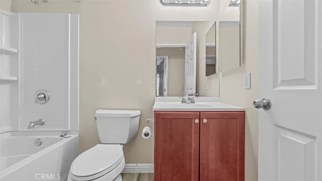 a bathroom with a toilet a sink a mirror a bathtub and vanity