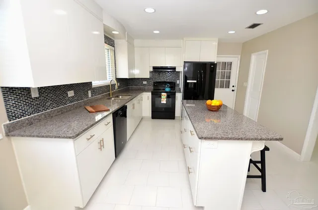 a kitchen with granite countertop a sink and a white wooden cabinets