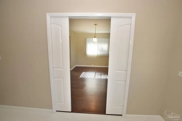a view of an empty room with a kitchen and a window