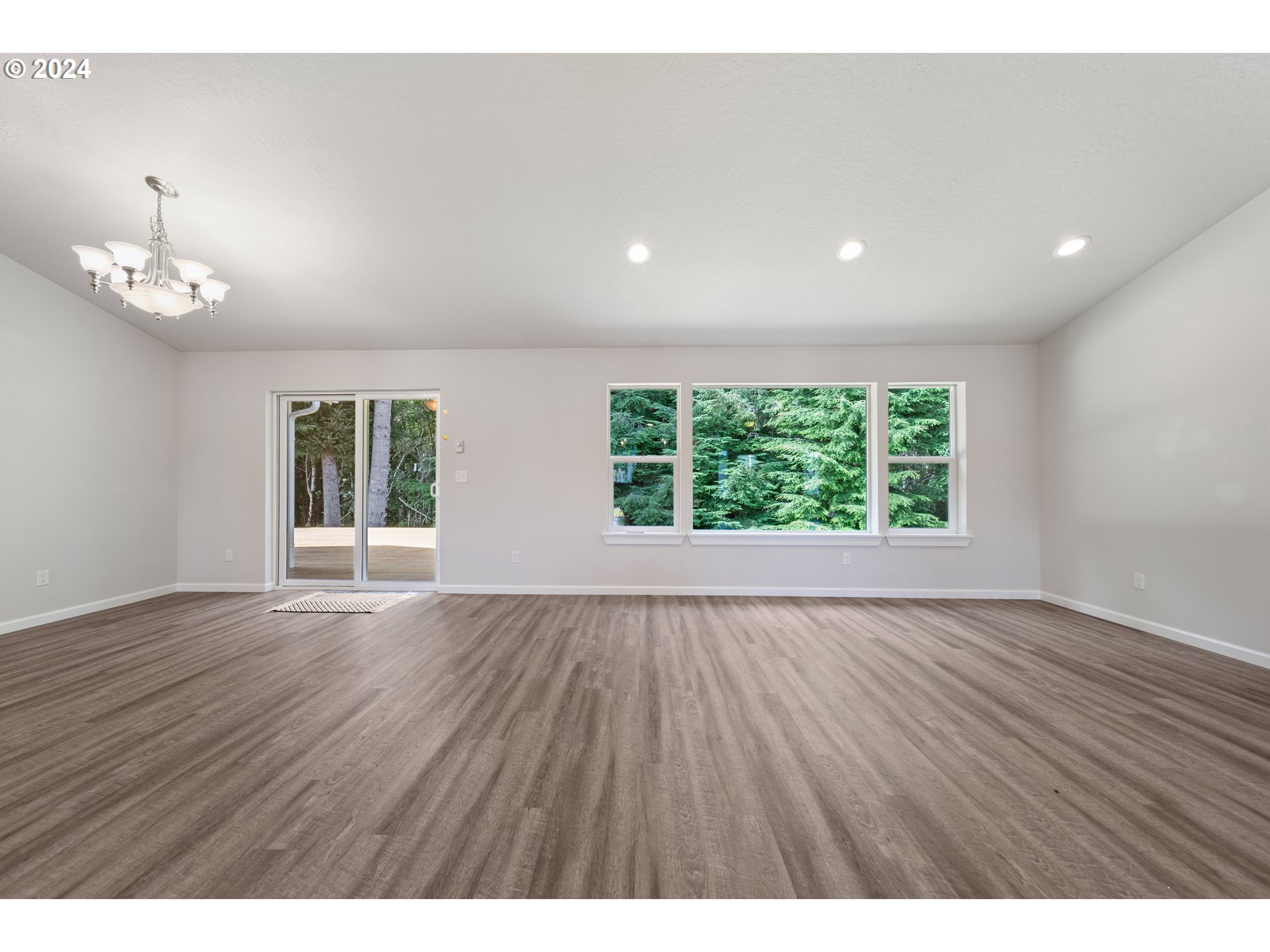 470 Providence Drive Reedsport, OR 97467 - Photo 8 of 41 an empty room with wooden floor and windows
