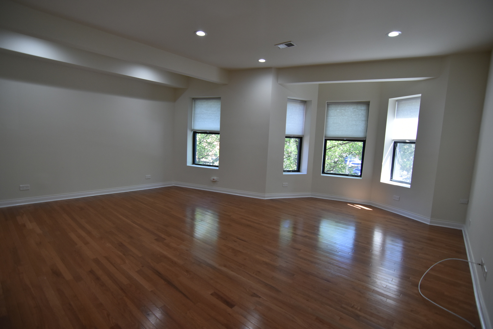 732 West Grace Street, Unit 2W Chicago, IL 60613 - Photo 3 of 15 an empty room with wooden floor and windows