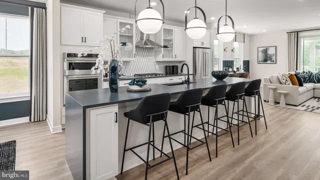 a kitchen with stainless steel appliances kitchen island granite countertop a table chairs sink and cabinets