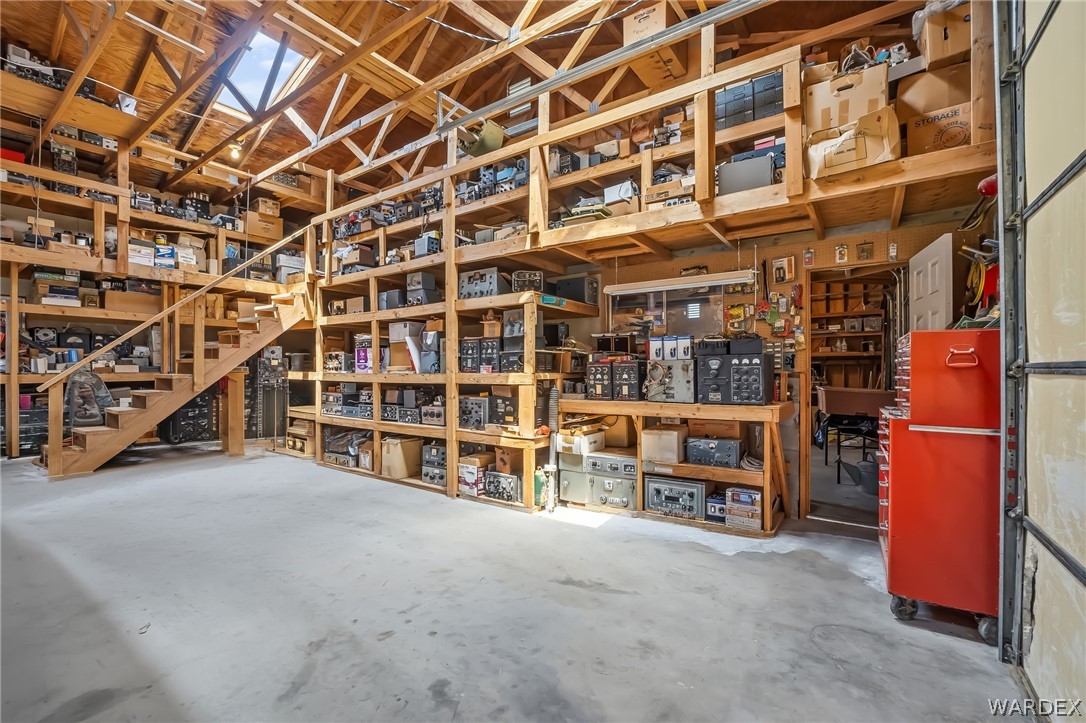 2401 North Stephan Road Kingman, AZ 86401 - Photo 64 of 92 Multi-level garage featuring extensive built-in wooden shelving, a concrete floor, exposed wood beam ceiling, and a skylight