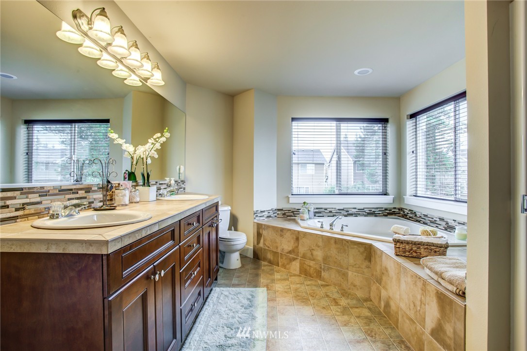 5117 Northeast 11th Street Renton, WA 98059 - Photo 13 of 19 a bathroom with a granite countertop sink a large mirror and a bathtub