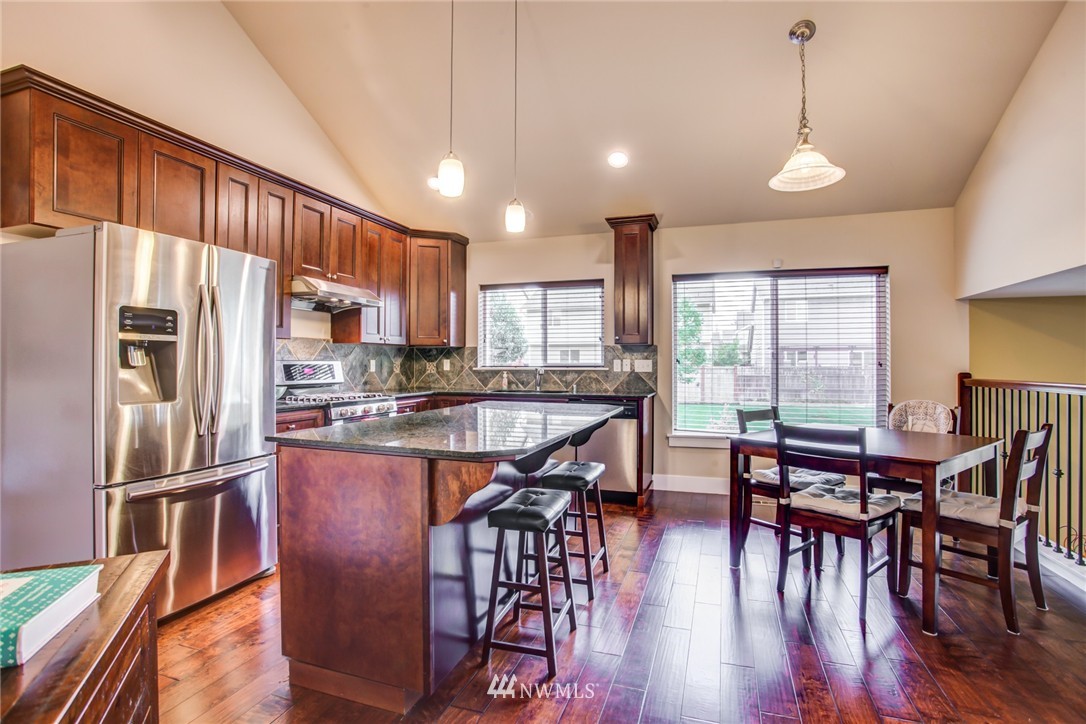 5117 Northeast 11th Street Renton, WA 98059 - Photo 7 of 19 a kitchen with stainless steel appliances granite countertop a refrigerator a stove a sink a dining table and chairs with wooden floor