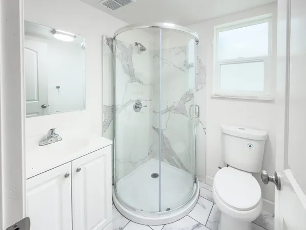 a bathroom with a toilet a sink a mirror and shower