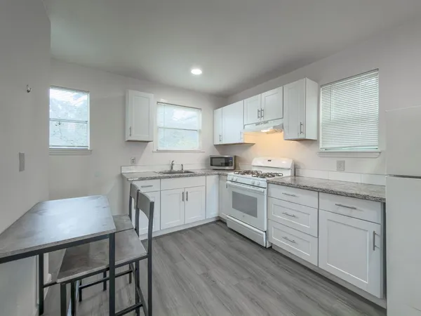 a kitchen with granite countertop white cabinets and white appliances