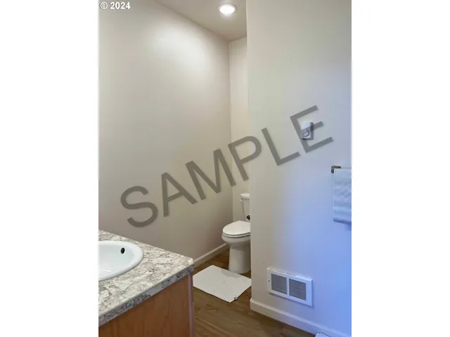 a bathroom with a granite countertop sink and a toilet