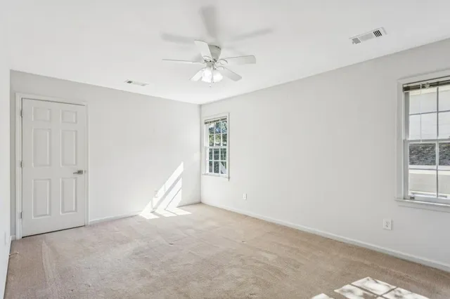an empty room with windows and fan