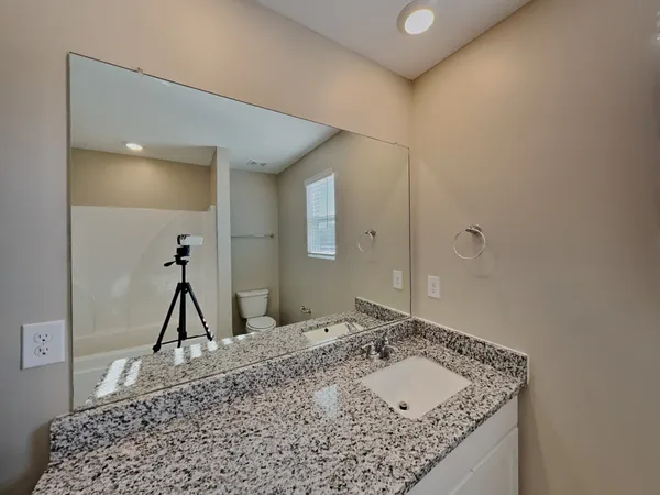 a bathroom with a granite countertop sink a toilet and a mirror