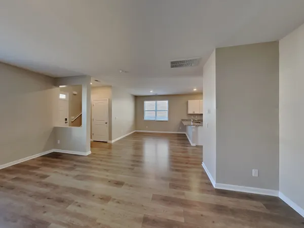 a view of a big room with wooden floor and a kitchen