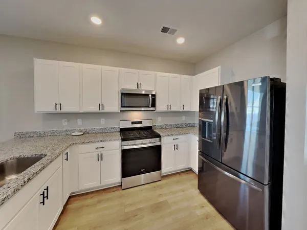 a kitchen with stainless steel appliances granite countertop a refrigerator sink and stove