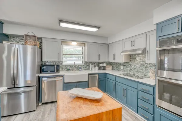 a kitchen with stainless steel appliances granite countertop lots of counter space and wooden floors