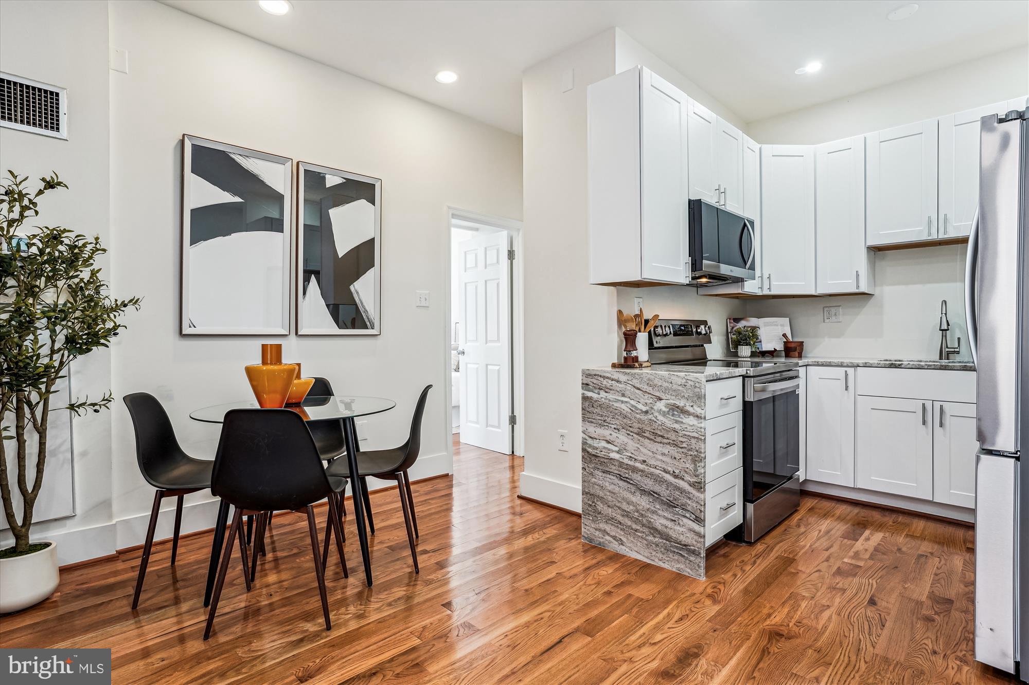 1615 Q Street Northwest, Unit 1012 Washington, DC 20009 - Photo 10 of 39 a kitchen with stainless steel appliances a stove top oven a sink a dining table and chairs with wooden floor