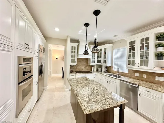 a large kitchen with stainless steel appliances kitchen island granite countertop a table chairs in it and a counter space