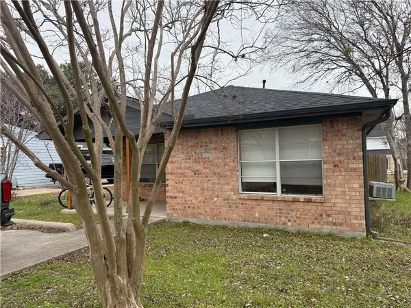 a view of a stone house with a large tree