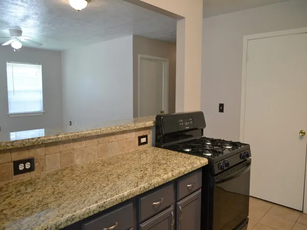 a kitchen with granite countertop a sink a stove and cabinets